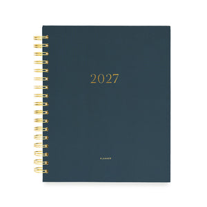 A 2027 spiral-bound planner with a dark navy blue cover and gold foil lettering with '2027' and 'planner' stamped on cover in gold