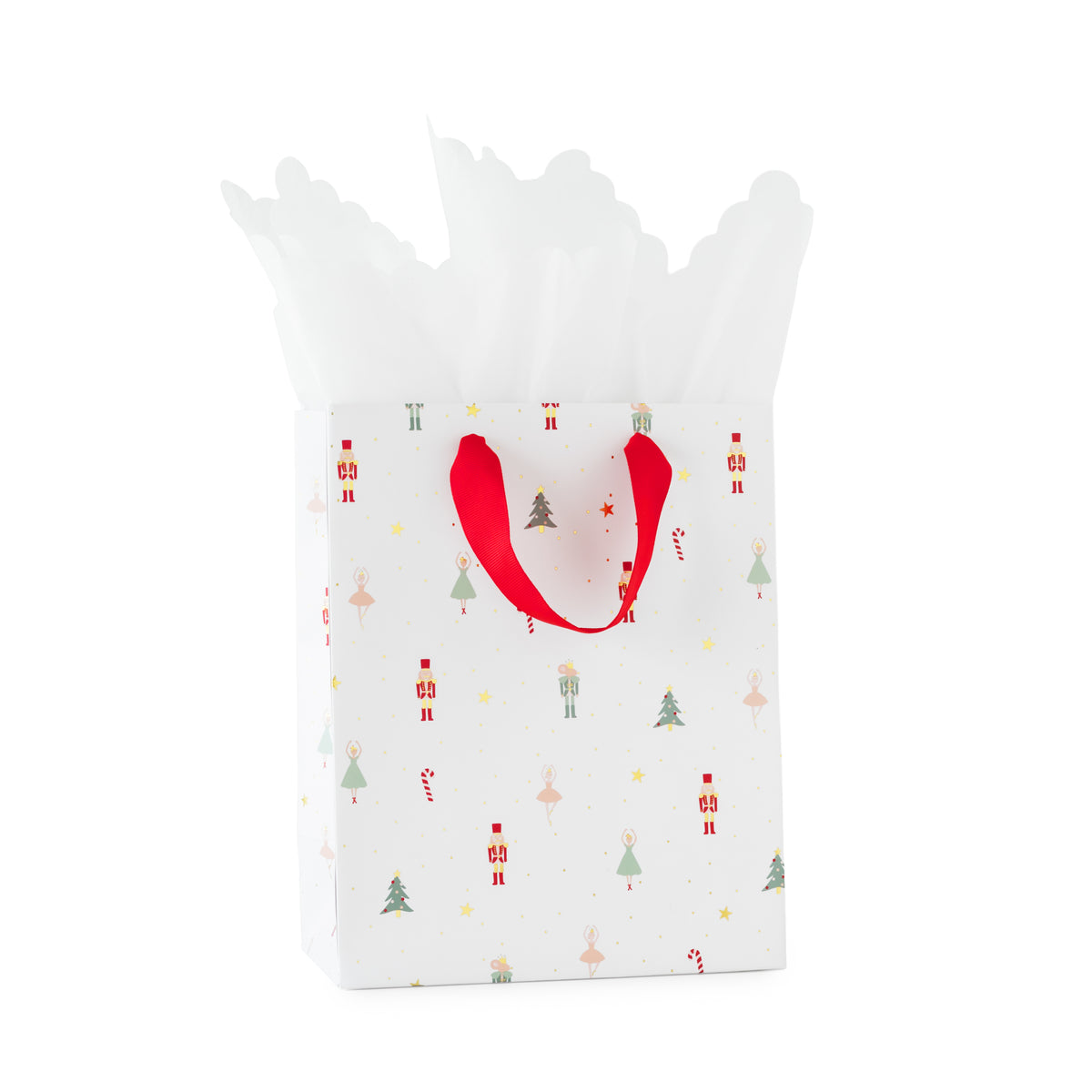 A white Christmas-themed nutcracker gift bag with red handles, decorated with small festive illustrations of nutcracker, mouse, trees, ballerina, and candy canes, filled with white tissue paper