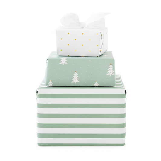 Three stacked gift boxes wrapped in coordinating holiday paper: a large white box with mint green horizontal stripes at the bottom, a medium mint green box with white Christmas trees, and a small white box with gold polka dots and a white bow on top