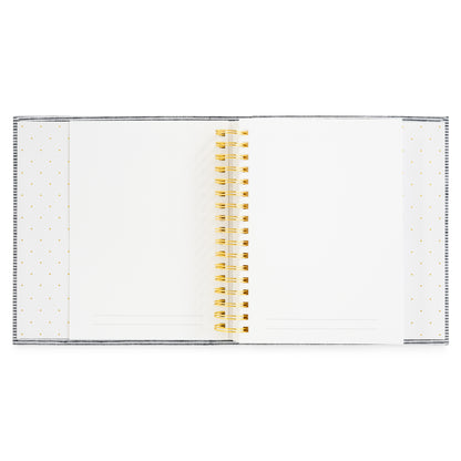 A white spiral-bound interior of the Halloween Book with a gold wire coil binding and delicate gold polka dot patterns on the left and right covers with white pages with gold lines at the bottom for prompts